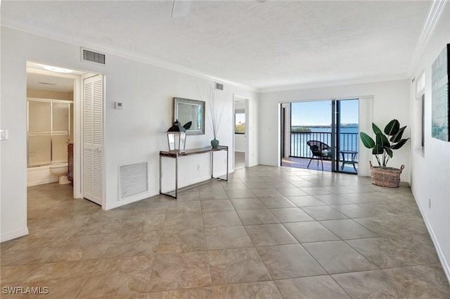 unfurnished room with a water view, a textured ceiling, and ornamental molding