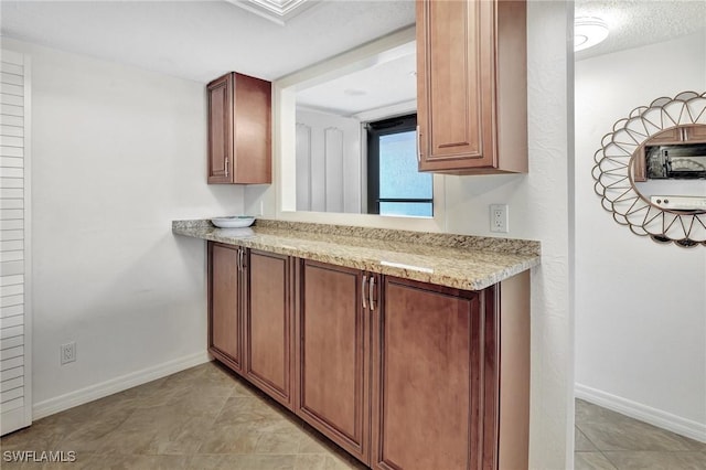 kitchen featuring light stone countertops, light tile patterned floors, and a textured ceiling