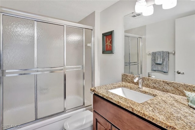 full bathroom with vanity, bath / shower combo with glass door, and toilet