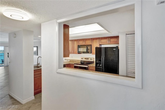 kitchen featuring sink, light tile patterned flooring, black appliances, and a textured ceiling