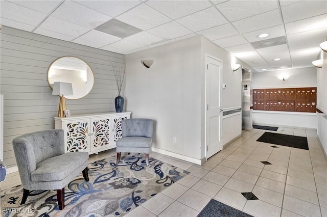 living area with a paneled ceiling, wooden walls, and light tile patterned floors