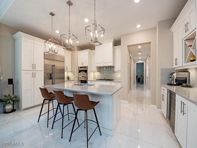 kitchen featuring a kitchen breakfast bar, white cabinetry, hanging light fixtures, and an island with sink