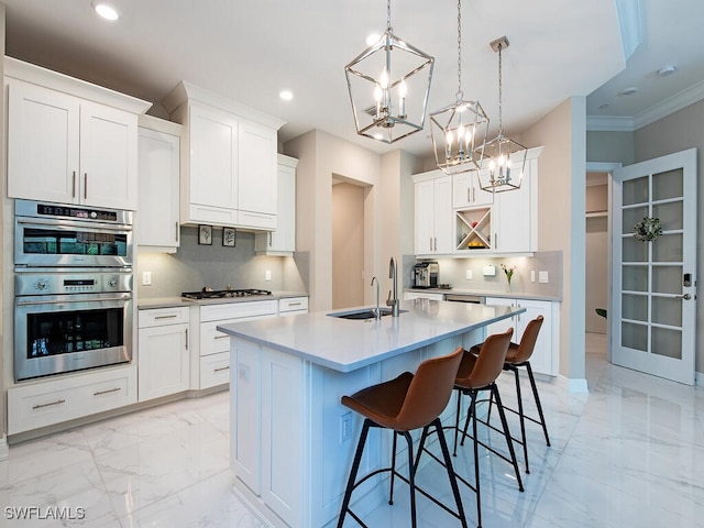 kitchen with a center island with sink, white cabinetry, stainless steel appliances, and tasteful backsplash