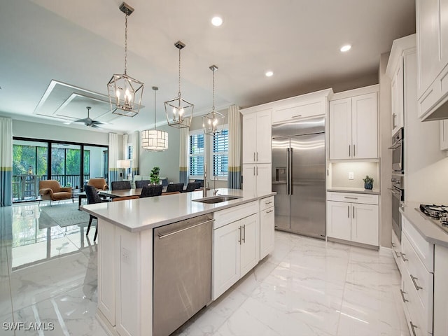 kitchen with a center island with sink, sink, hanging light fixtures, ceiling fan, and stainless steel appliances