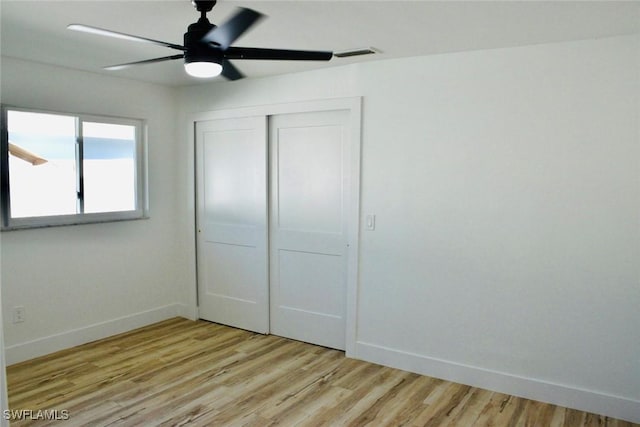 unfurnished bedroom featuring ceiling fan, a closet, and light wood-type flooring