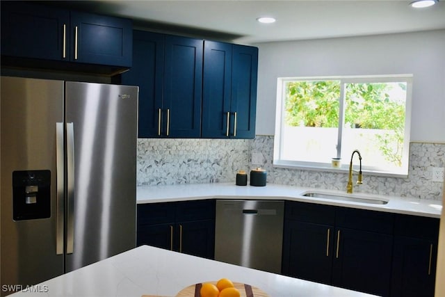 kitchen with blue cabinetry, decorative backsplash, sink, and stainless steel appliances