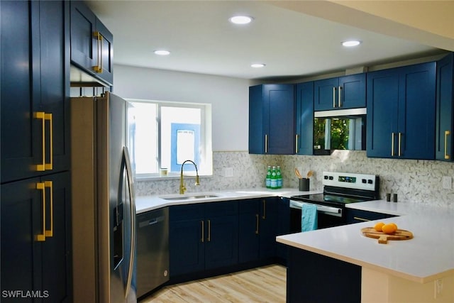 kitchen featuring blue cabinetry, sink, backsplash, black appliances, and light wood-type flooring