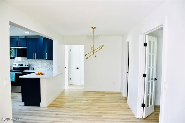 kitchen featuring backsplash, blue cabinetry, appliances with stainless steel finishes, a notable chandelier, and light hardwood / wood-style floors