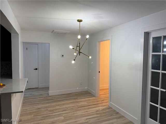 unfurnished dining area with light hardwood / wood-style flooring and a chandelier