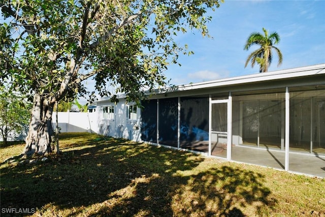 back of property featuring a lawn and a sunroom