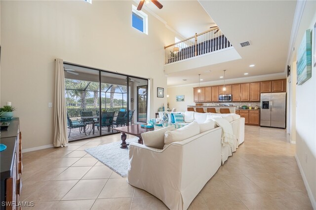 living room with crown molding, light tile patterned floors, a high ceiling, and ceiling fan