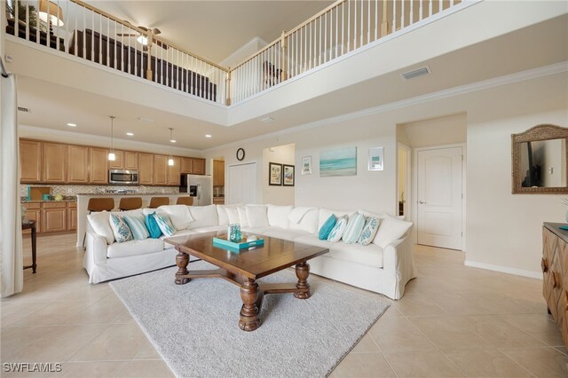 tiled living room with crown molding and a high ceiling