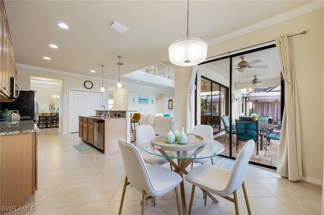 dining area featuring ceiling fan, sink, light tile patterned floors, and crown molding