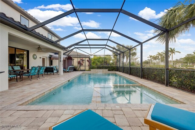 view of swimming pool featuring glass enclosure, ceiling fan, and a patio area