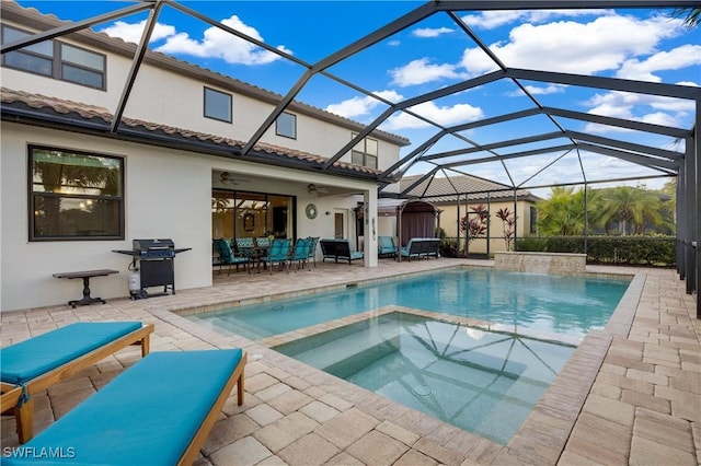 view of pool with a pool with connected hot tub, area for grilling, glass enclosure, ceiling fan, and a patio area