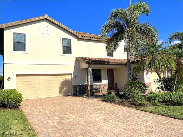 view of front of house featuring stucco siding, an attached garage, a tiled roof, decorative driveway, and covered porch