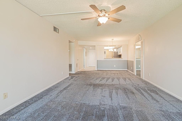 unfurnished living room with a textured ceiling, ceiling fan with notable chandelier, visible vents, and carpet floors