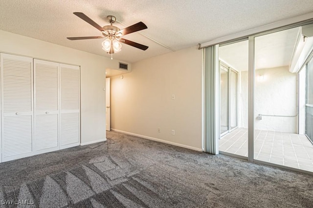 unfurnished bedroom with a textured ceiling, a closet, ceiling fan, and carpet floors