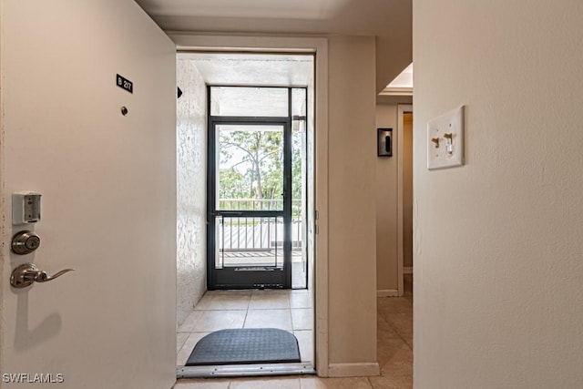 doorway with light tile patterned floors and baseboards