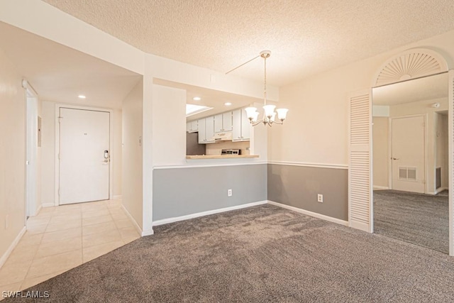 interior space with a chandelier, visible vents, light carpet, and a textured ceiling