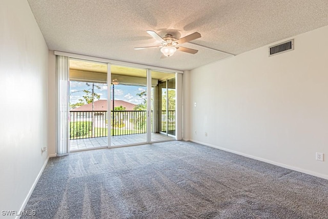 carpeted empty room with visible vents, a textured ceiling, a ceiling fan, and floor to ceiling windows