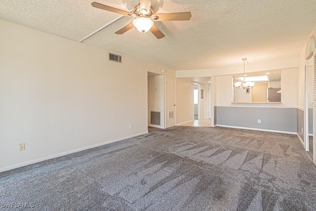 carpeted empty room featuring a textured ceiling, ceiling fan with notable chandelier, baseboards, and visible vents