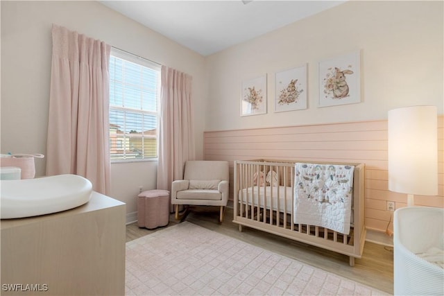 bedroom featuring a nursery area and light hardwood / wood-style flooring