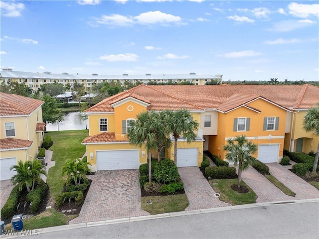 view of front of home with a garage, a front yard, and a water view