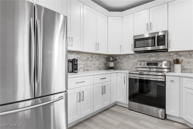 kitchen featuring stainless steel appliances, tasteful backsplash, and white cabinets