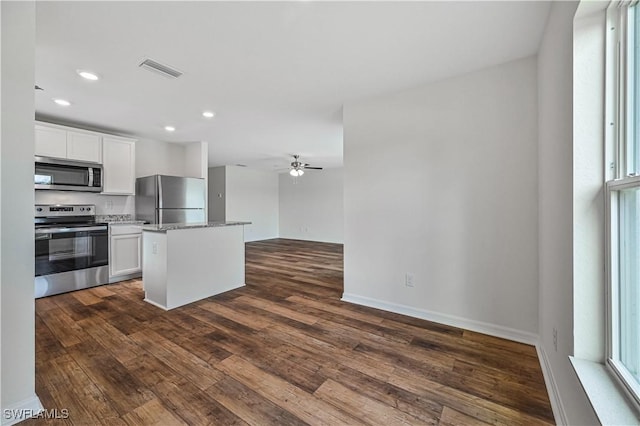 kitchen with white cabinets, appliances with stainless steel finishes, a center island, and light stone counters