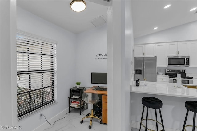 kitchen featuring stainless steel appliances, kitchen peninsula, vaulted ceiling, a breakfast bar area, and white cabinets