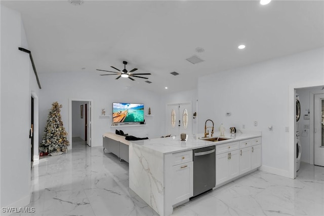 kitchen featuring white cabinets, stacked washer and dryer, sink, stainless steel dishwasher, and ceiling fan