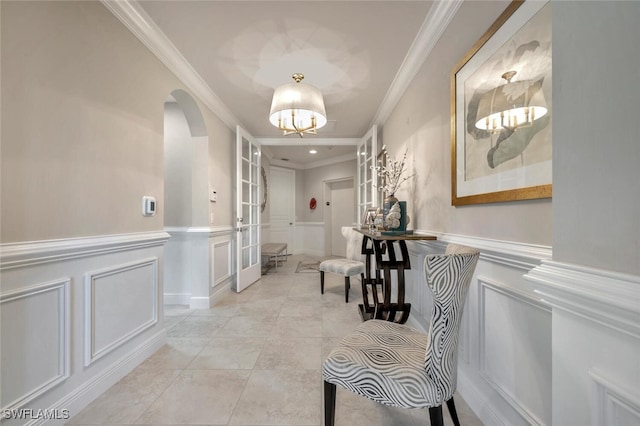 hall with a wainscoted wall, arched walkways, a decorative wall, and crown molding