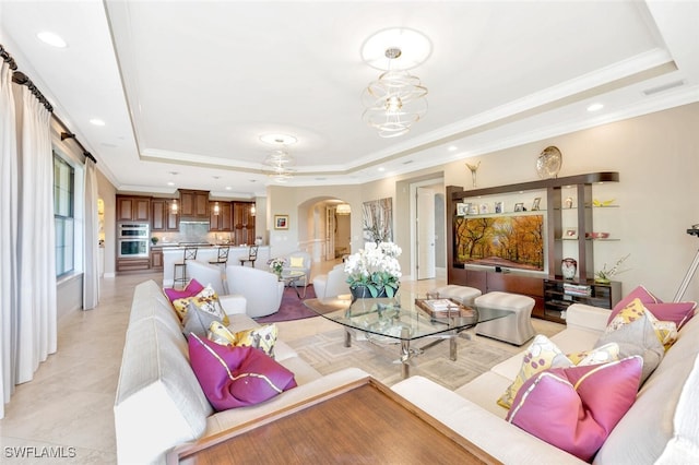 living room featuring arched walkways, ornamental molding, a raised ceiling, and recessed lighting