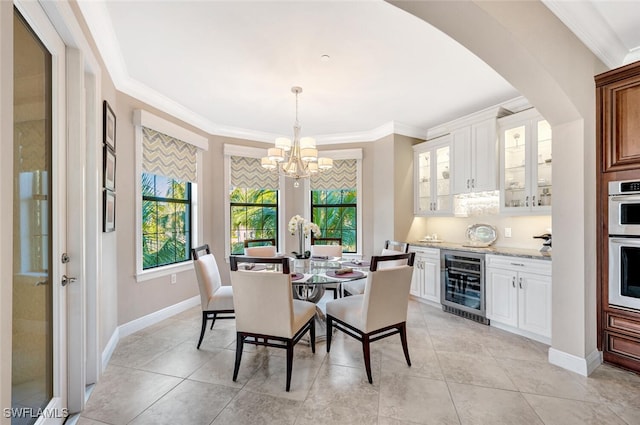 dining area with a chandelier, wine cooler, crown molding, and baseboards