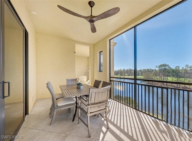 sunroom with ceiling fan and a water view