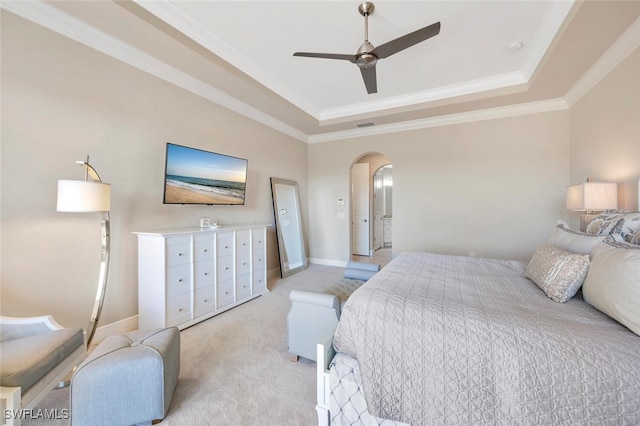 bedroom with arched walkways, a tray ceiling, crown molding, and light colored carpet