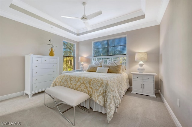 bedroom featuring light carpet, baseboards, a raised ceiling, and crown molding