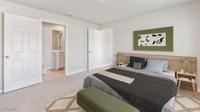 bedroom featuring light carpet, ensuite bathroom, visible vents, and baseboards