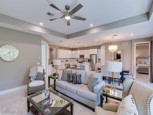 living room featuring ceiling fan with notable chandelier