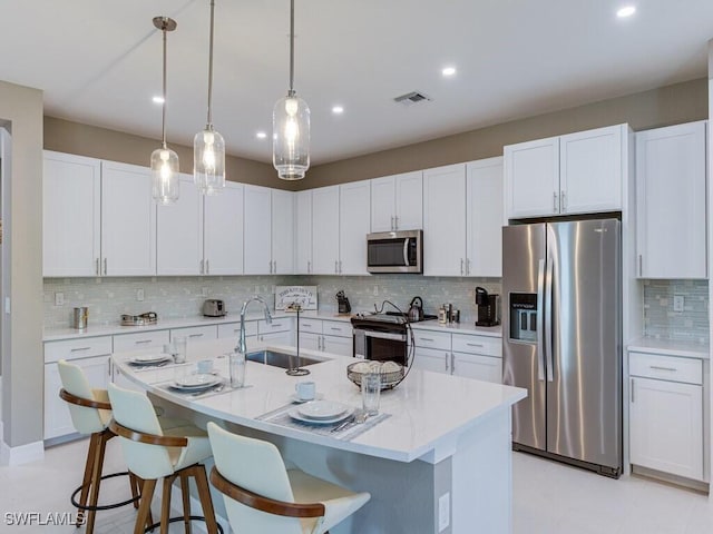 kitchen with a breakfast bar area, sink, white cabinets, and stainless steel appliances