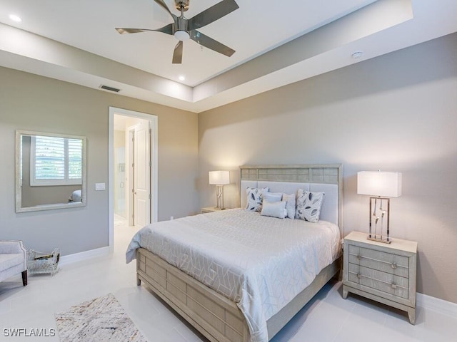 bedroom featuring ceiling fan, a raised ceiling, and connected bathroom