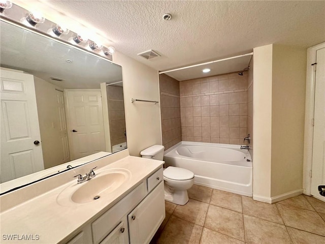 full bathroom with vanity, tile patterned floors, tiled shower / bath, toilet, and a textured ceiling