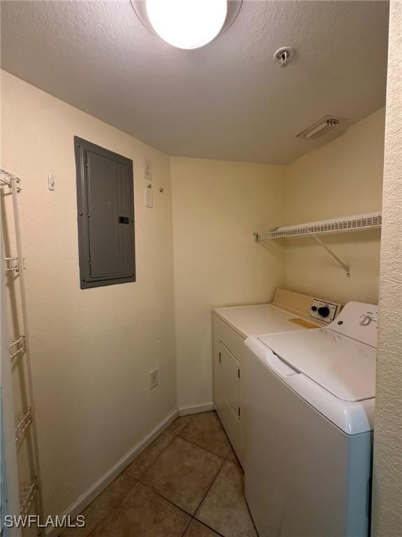 laundry area with separate washer and dryer, electric panel, light tile patterned floors, and a textured ceiling