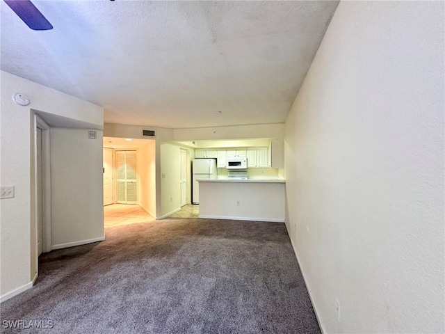 unfurnished living room featuring light carpet and ceiling fan