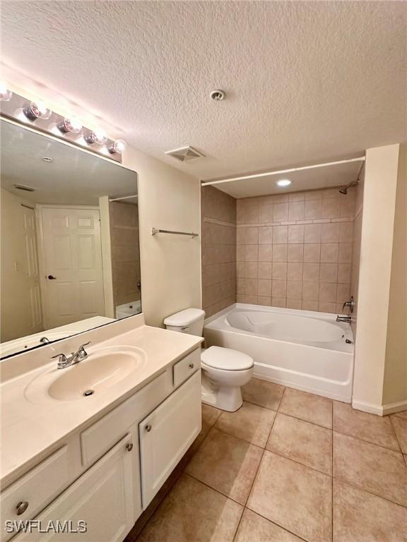 full bathroom with tile patterned floors, tiled shower / bath combo, a textured ceiling, and toilet