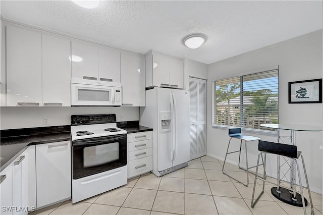 kitchen featuring a textured ceiling, light tile patterned floors, white cabinets, and white appliances