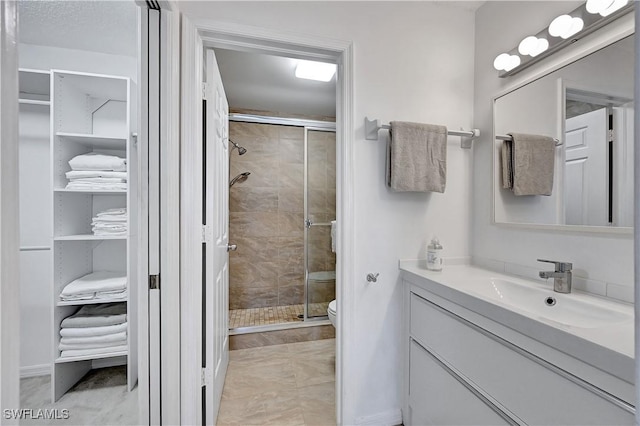 bathroom with tile patterned floors, toilet, an enclosed shower, and vanity