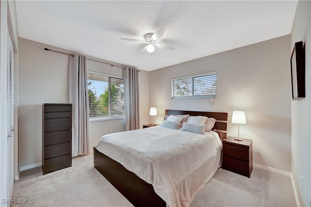 bedroom featuring multiple windows, light carpet, a closet, and ceiling fan