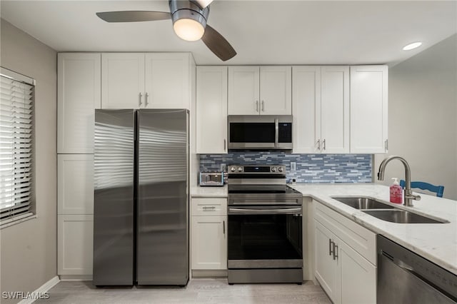 kitchen featuring light stone countertops, sink, white cabinets, and appliances with stainless steel finishes